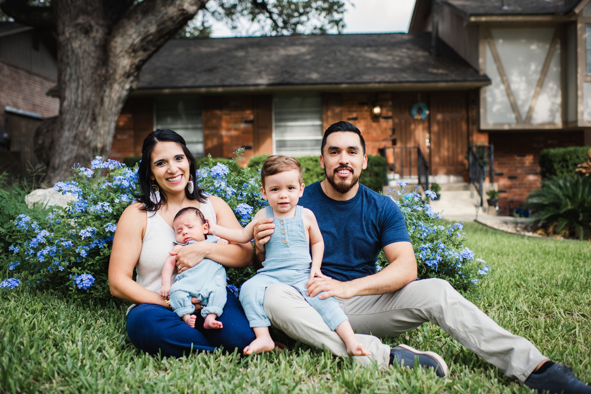 Family sitting with newborn baby sitting in the grass, San Antonio newborn photographer