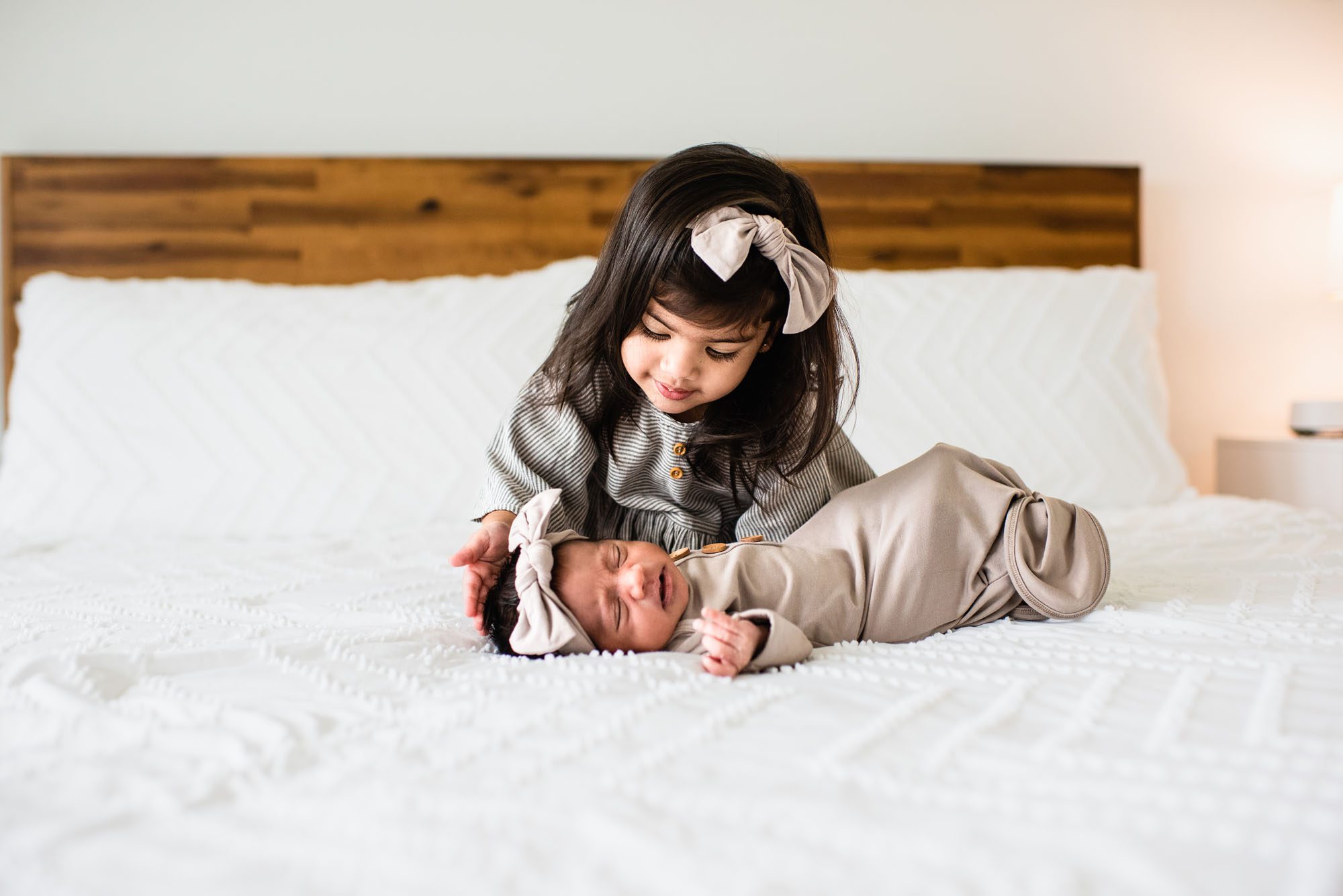 Sister patting newborn baby on bed, San Antonio newborn photographer