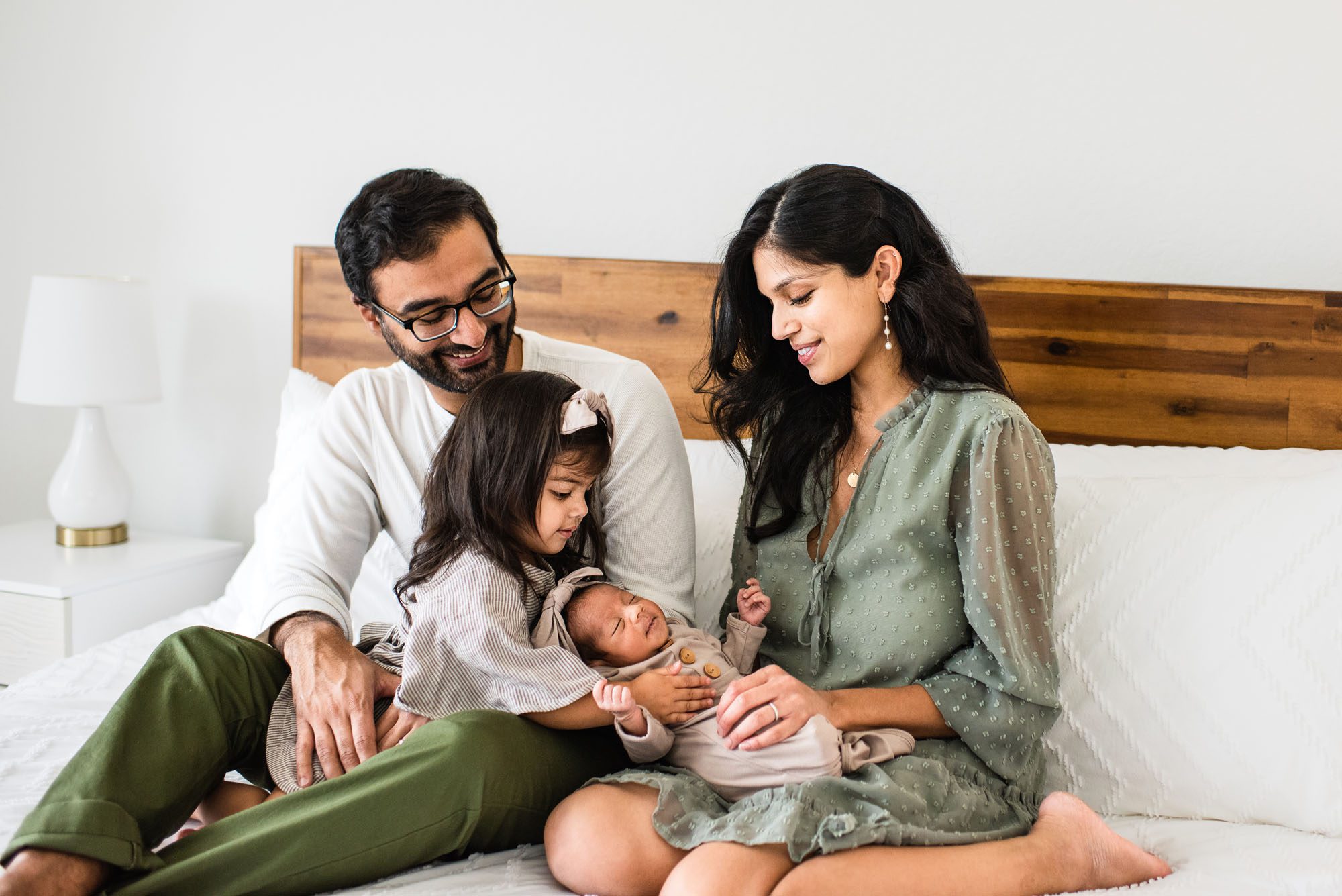 Family sitting together on bed with newborn baby, San Antonio lifestyle photographer