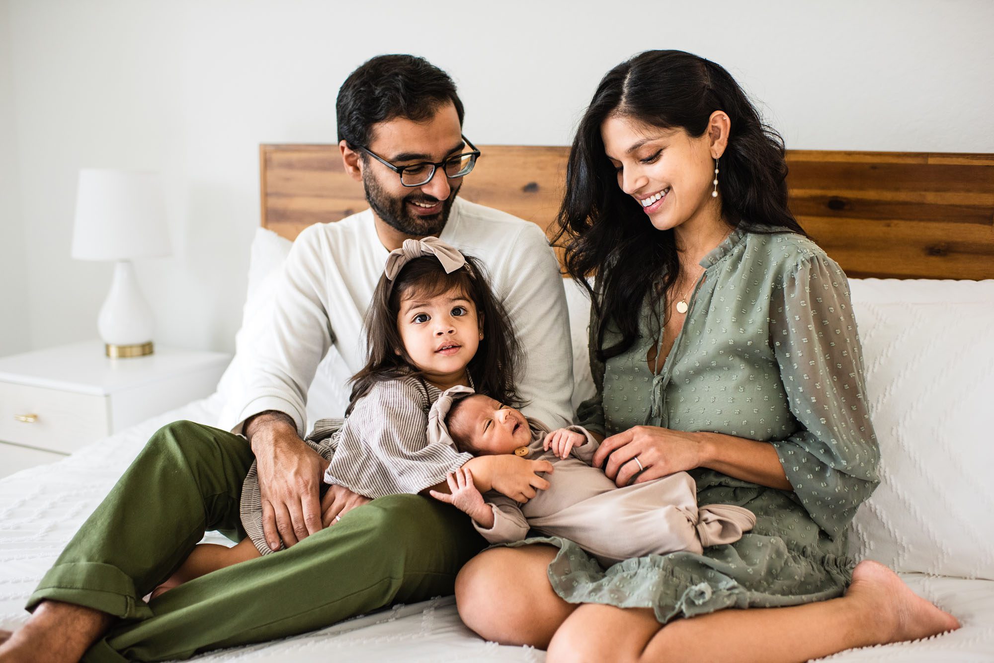 Family sitting together on bed with newborn baby, San Antonio lifestyle newborn photographer