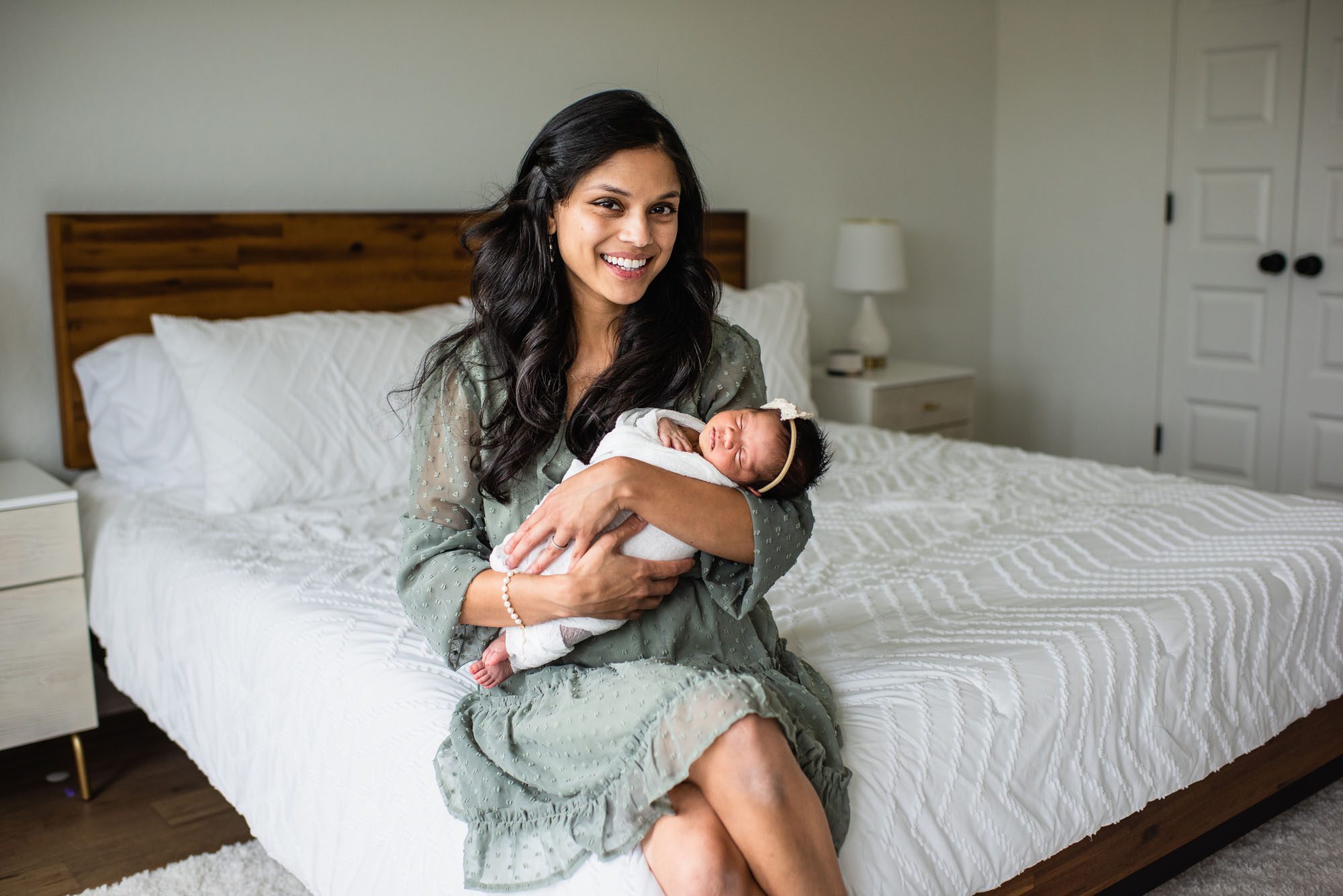 Mother in green dress holding newborn daughter, San Antonio Newborn Photographer