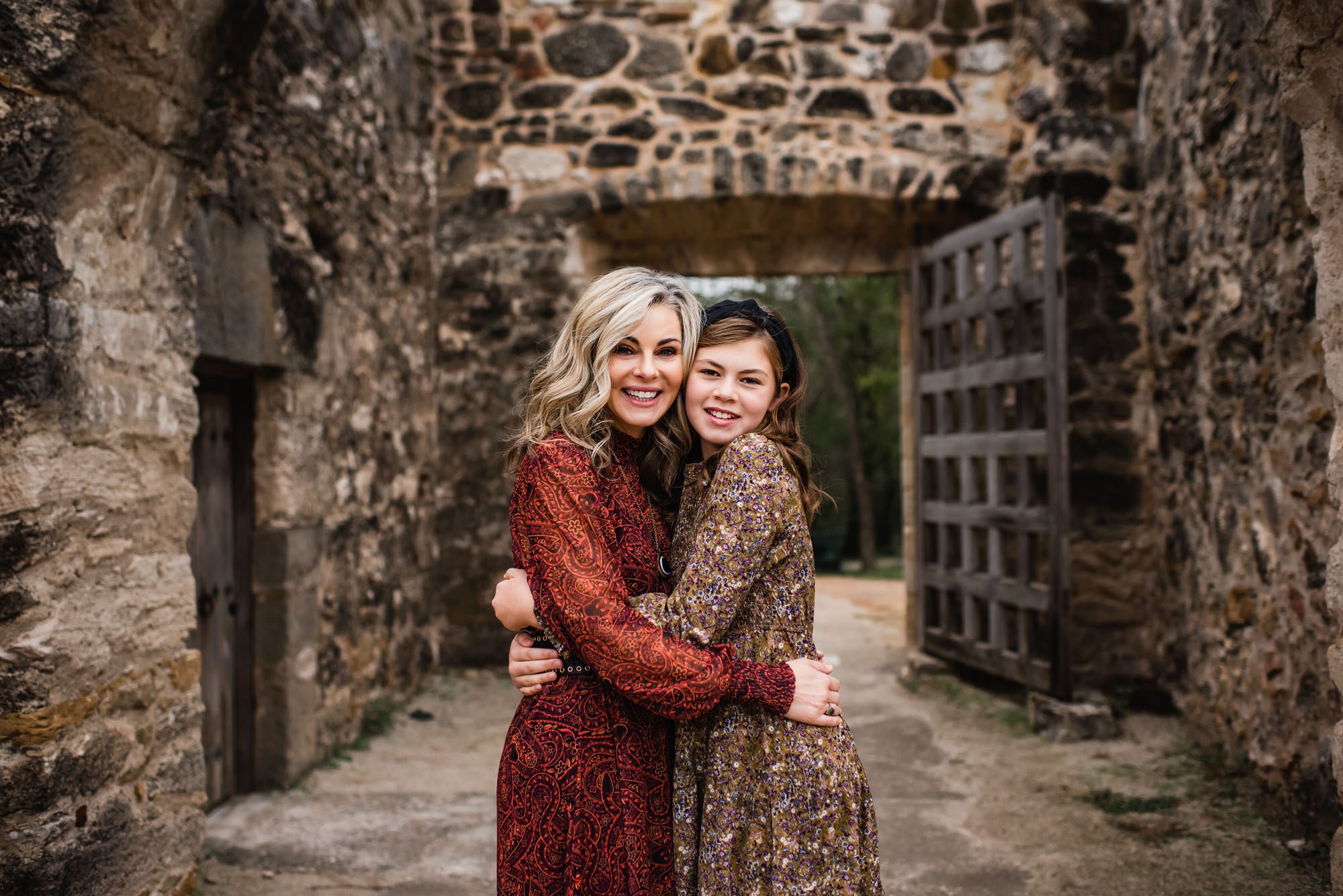 Mother and daughter hugging near brown stone wall, San Antonio lifestyle photographer
