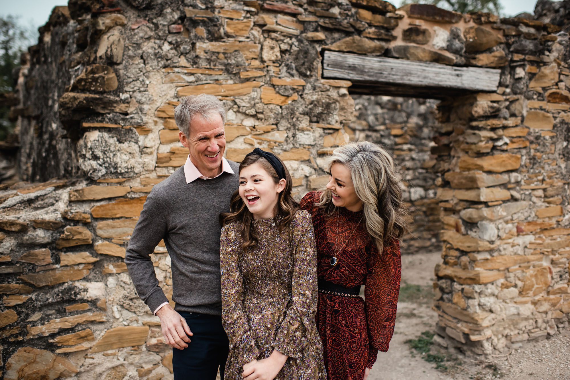 Family laughing in front of stone wall, San Antonio lifestyle photographer