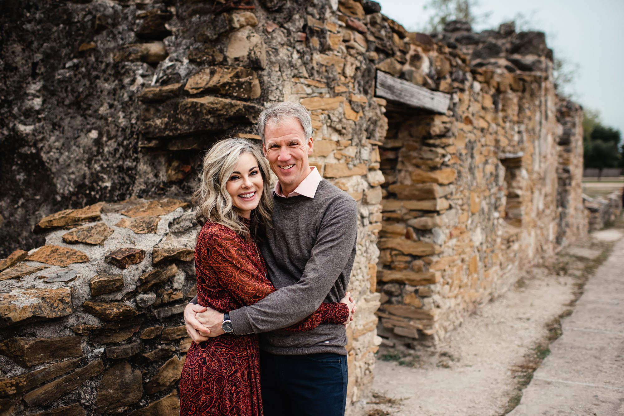 Couple hugging and standing by stone wall, San Antonio family photographer
