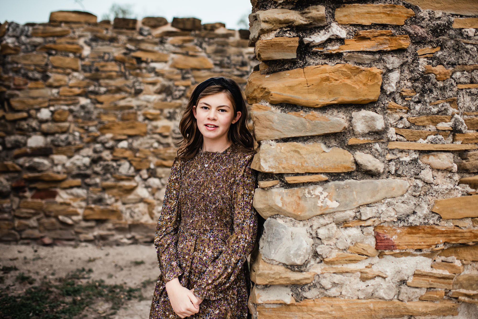 Portrait of girl standing by stone wall, San Antonio family photographer
