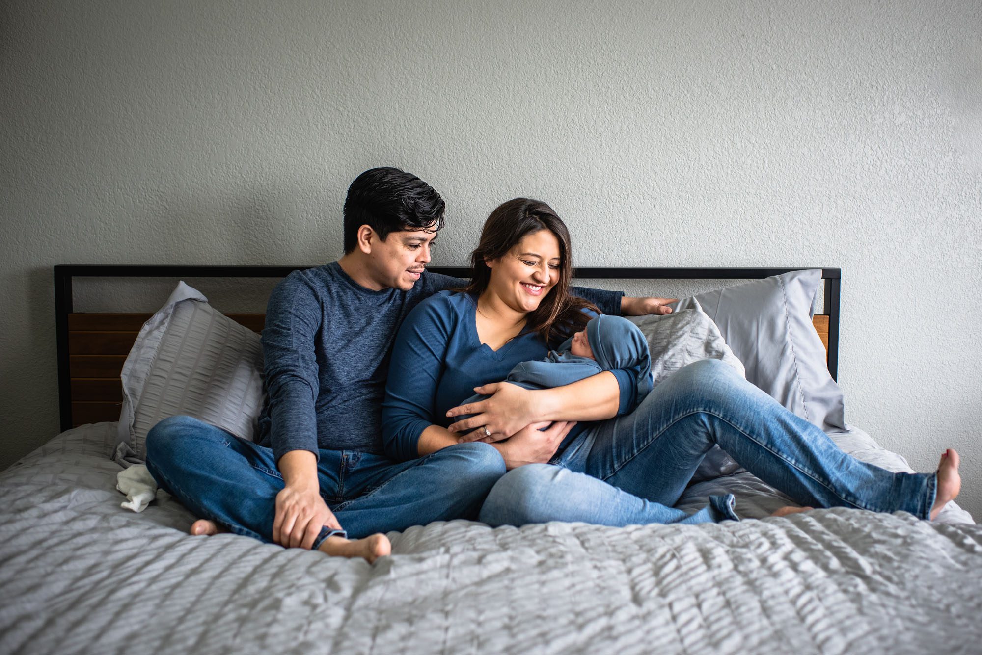 Parents sitting on bed with newborn baby, San Antonio Lifestyle Newborn Photographer