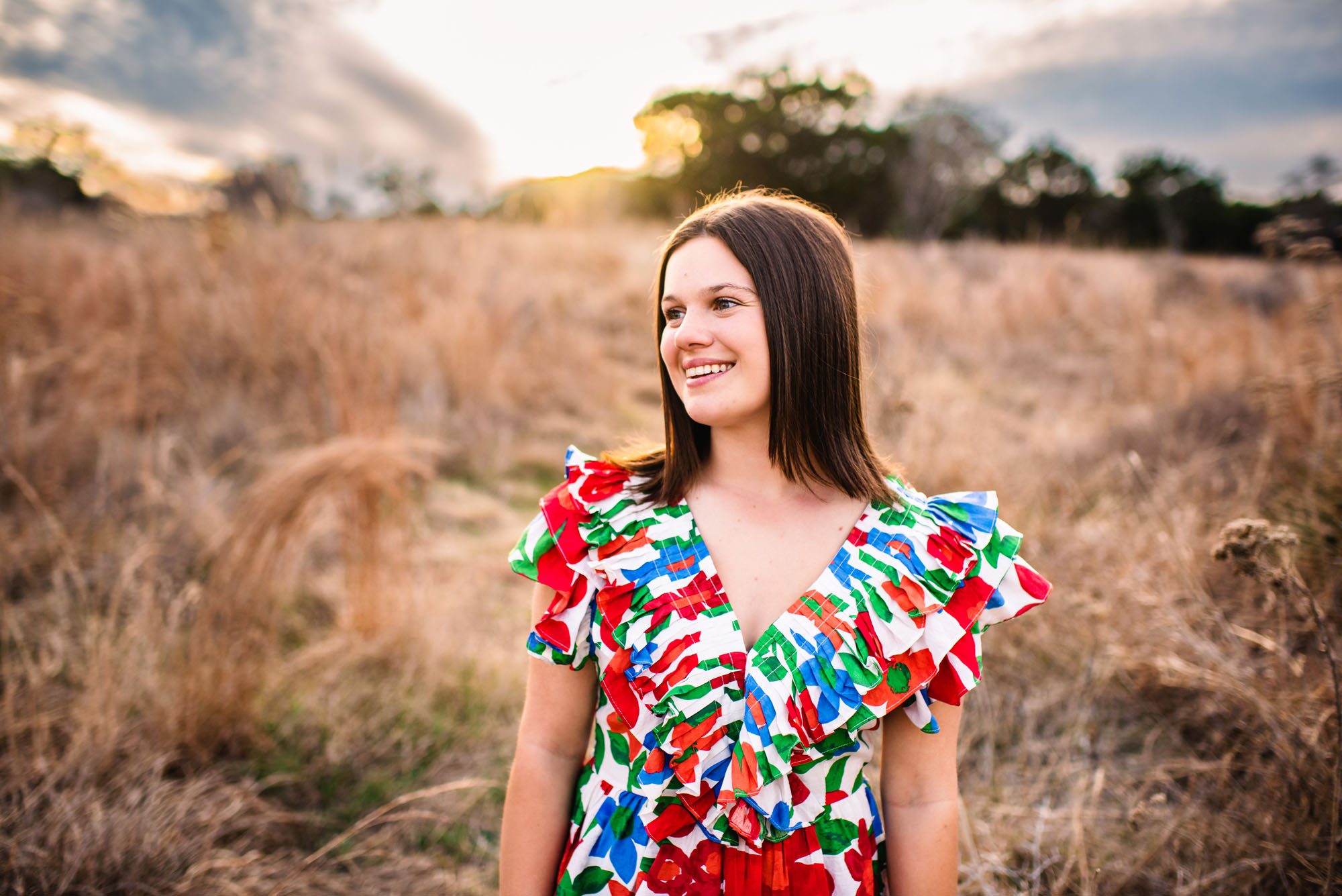 Senior girl in a brightly colored top in a field at sunset, San Antonio senior photographer