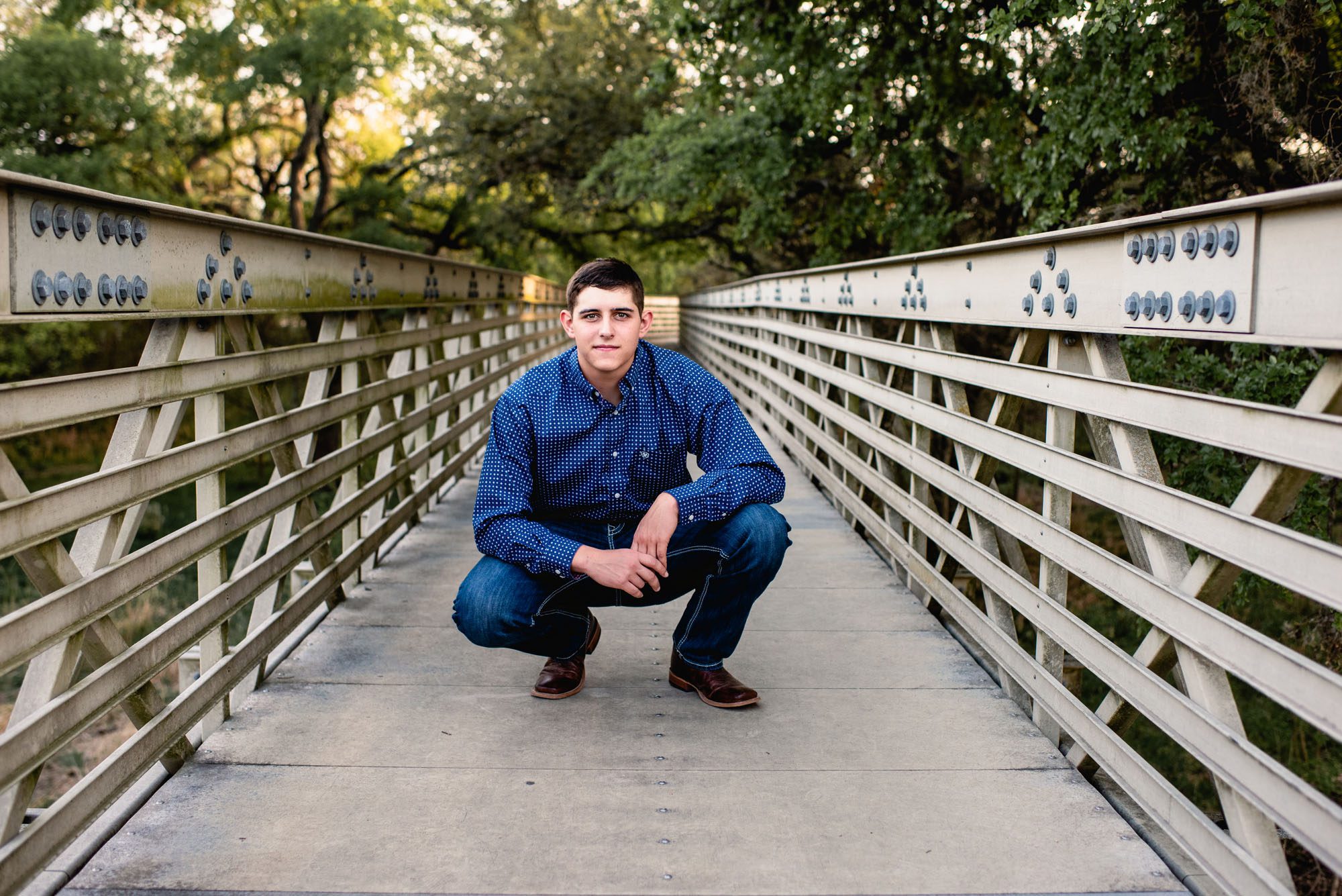Boy squatting down on a bridge, San Antonio senior photographer
