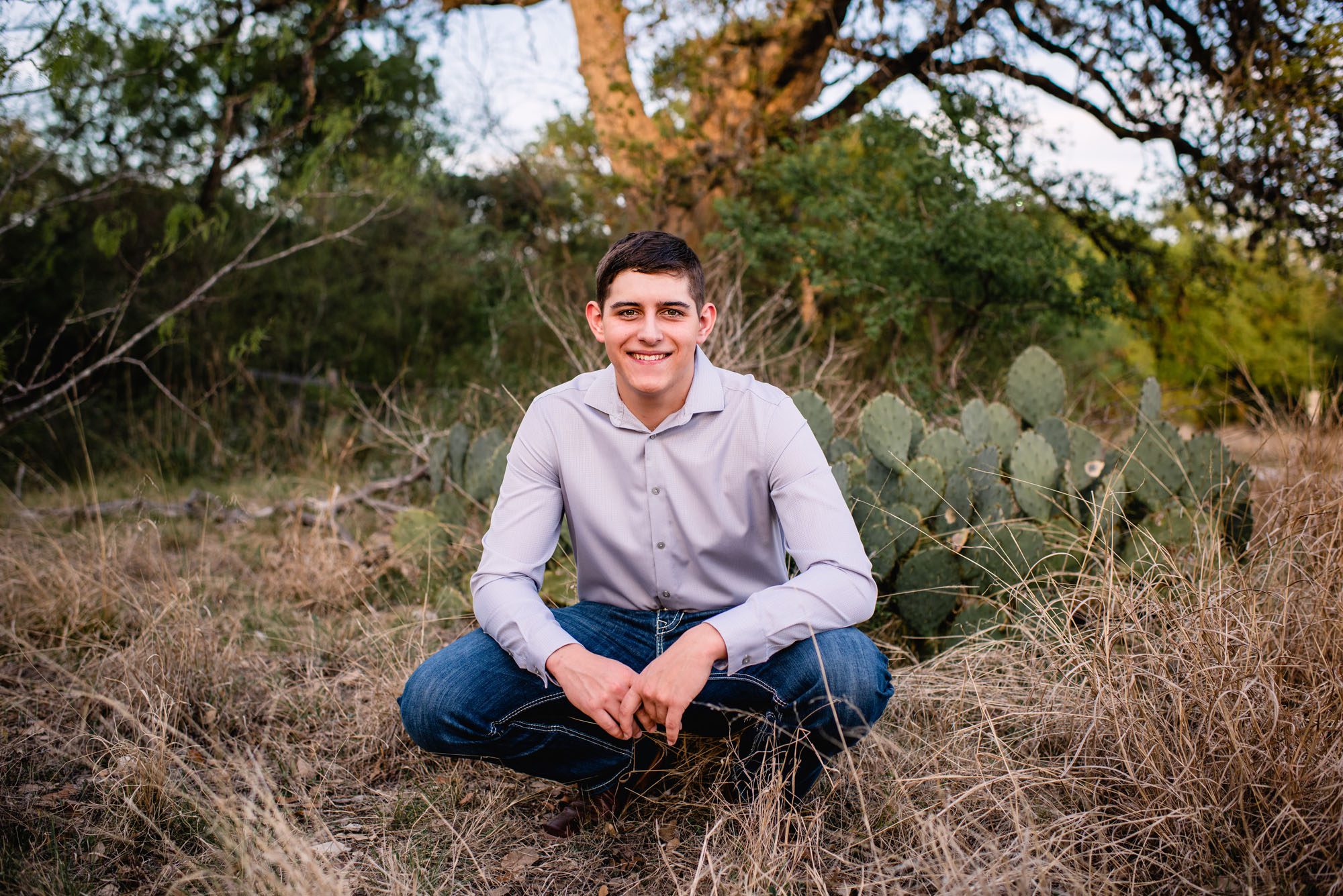 Senior boy squatting down by a cactus, San Antonio senior photographer