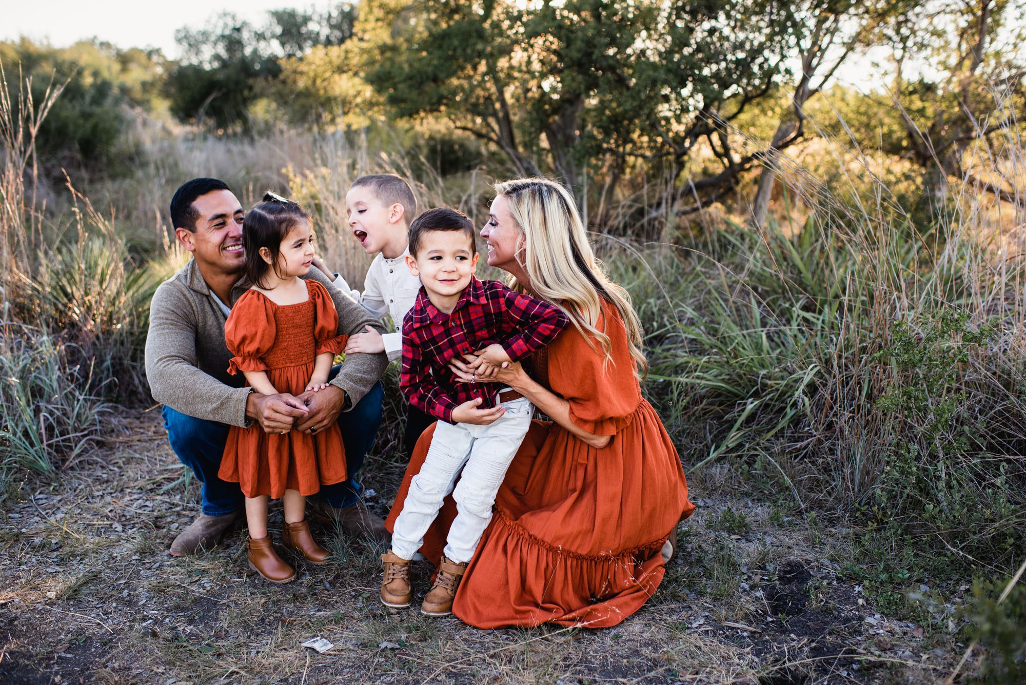 Family smiling at one another in the grass, San Antonio family photographer