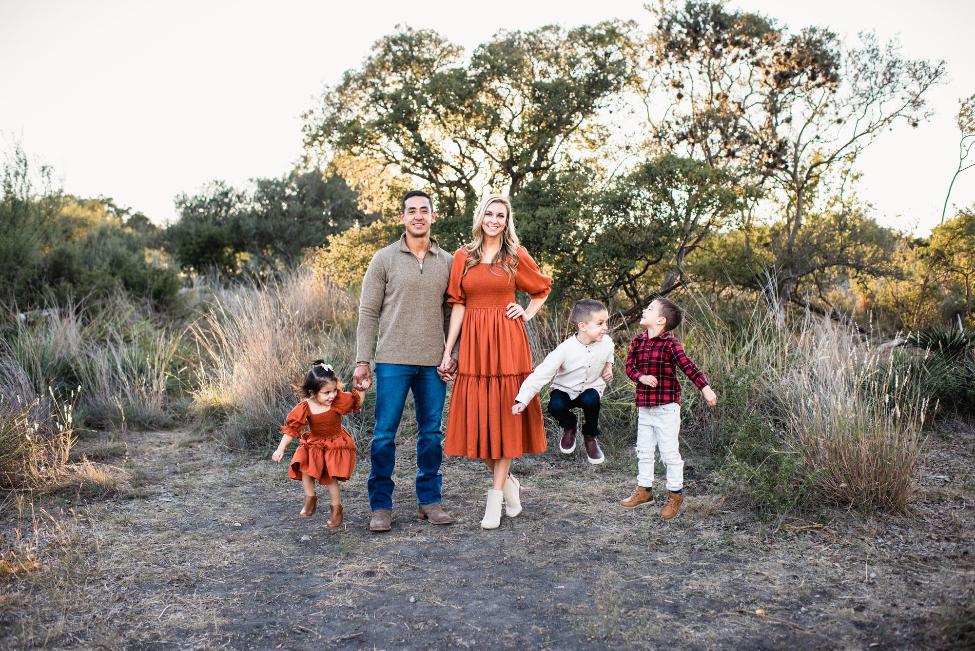 Kids jumping around parents in a field, San Antonio lifestyle photographer