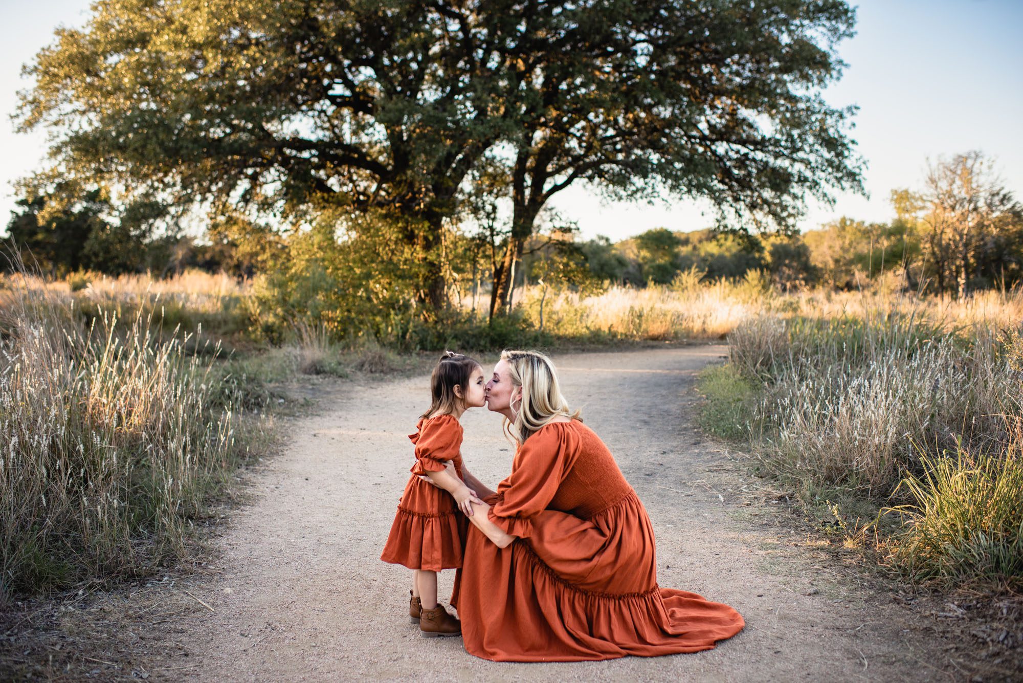 Mother kissing daughter on a path in a field, San Antonio lifestyle family photographer