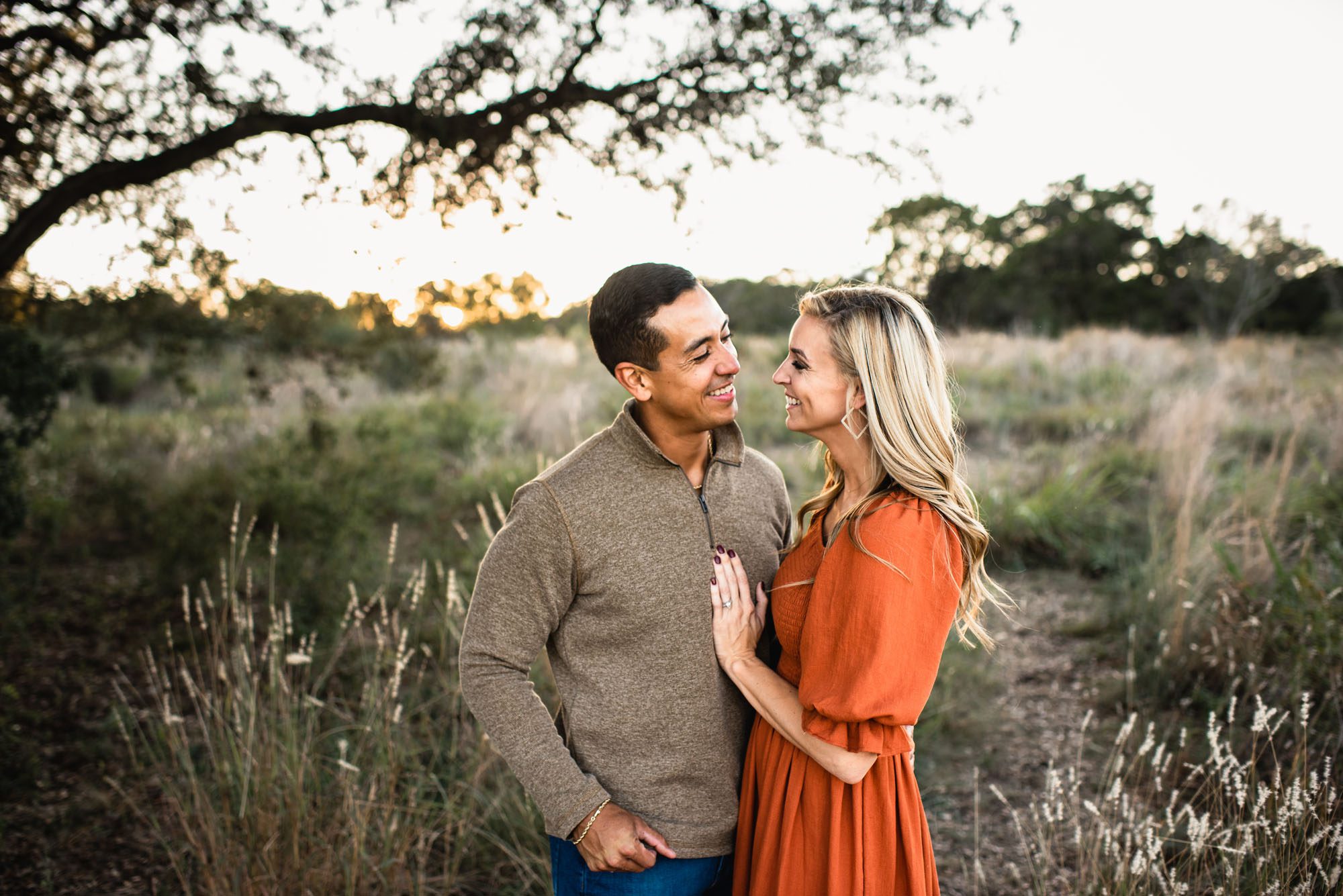 Couple smiling at each other in a field with tall grass, San Antonio family photographer