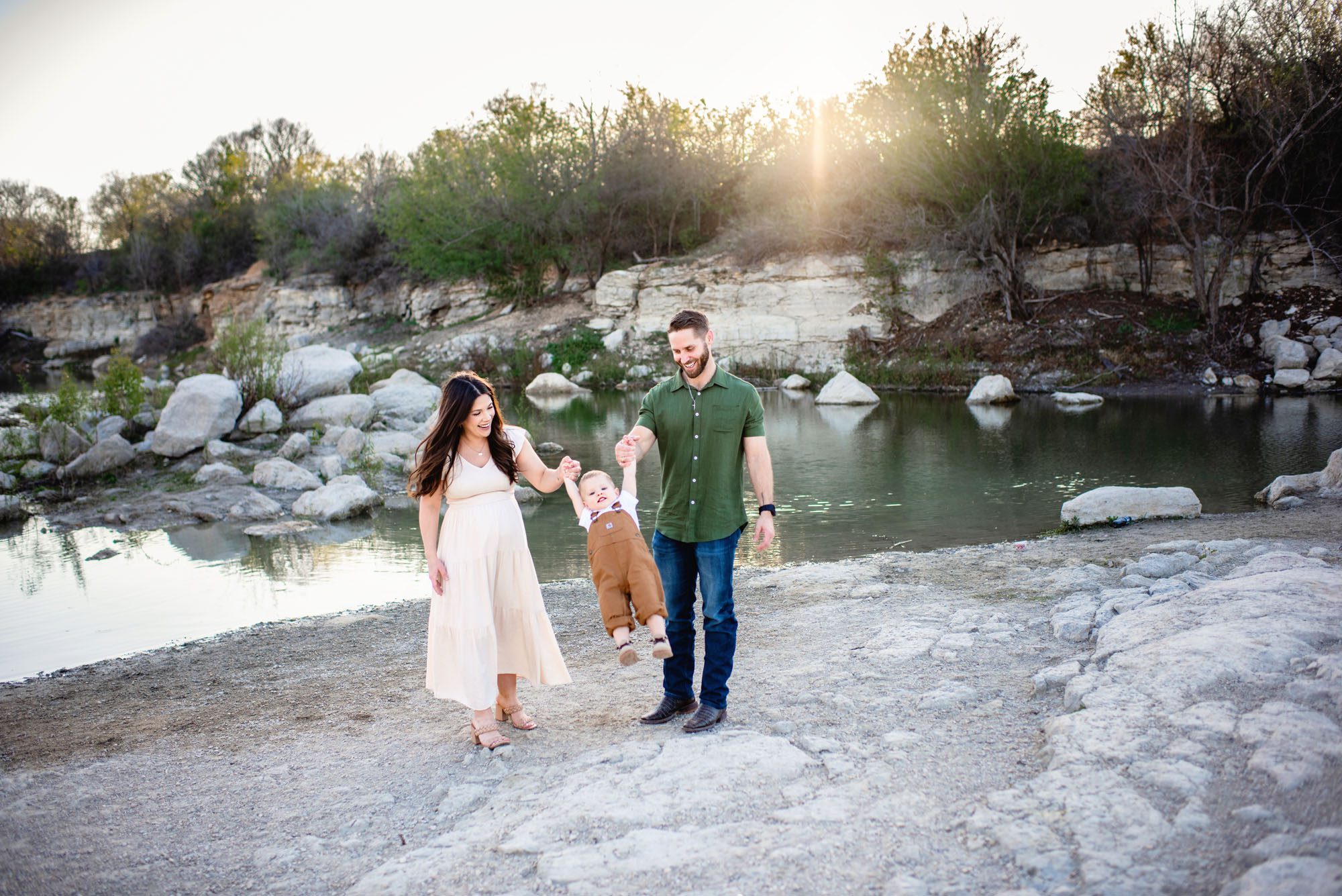 Family playing swing with son by a lake at sunset, San Antonio maternity photographer