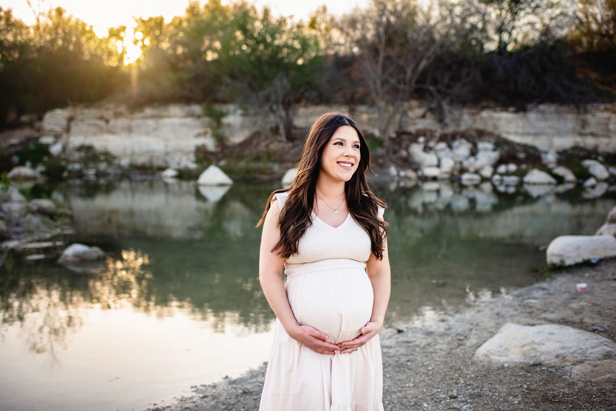 Pregnant mom smiling by a lake at sunset, San Antonio maternity photographer