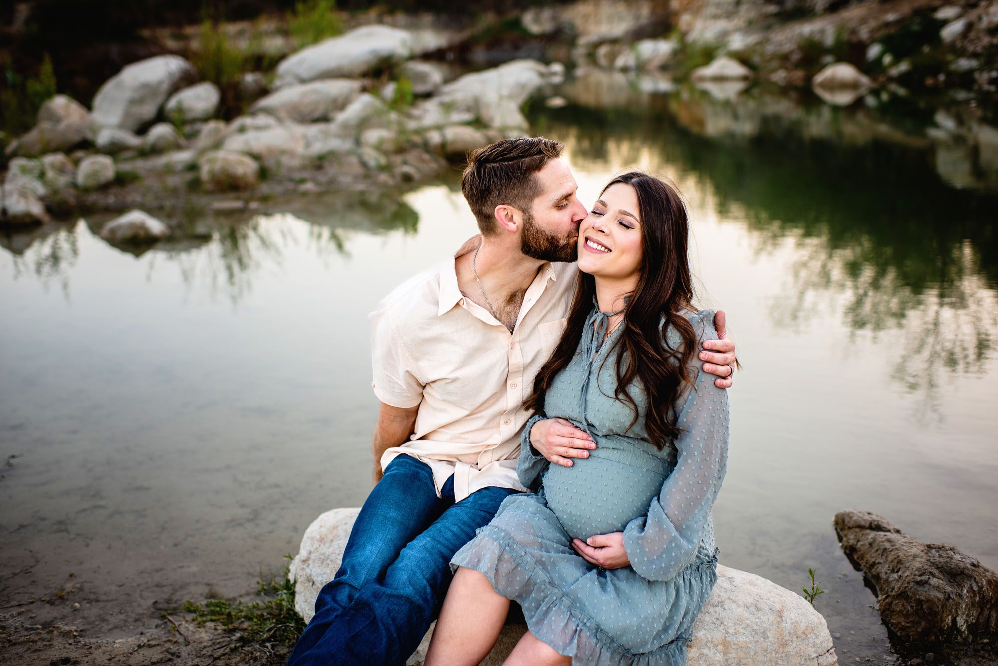 Husband kissing wife's cheek by the lake, Maternity photographer in San Antonio