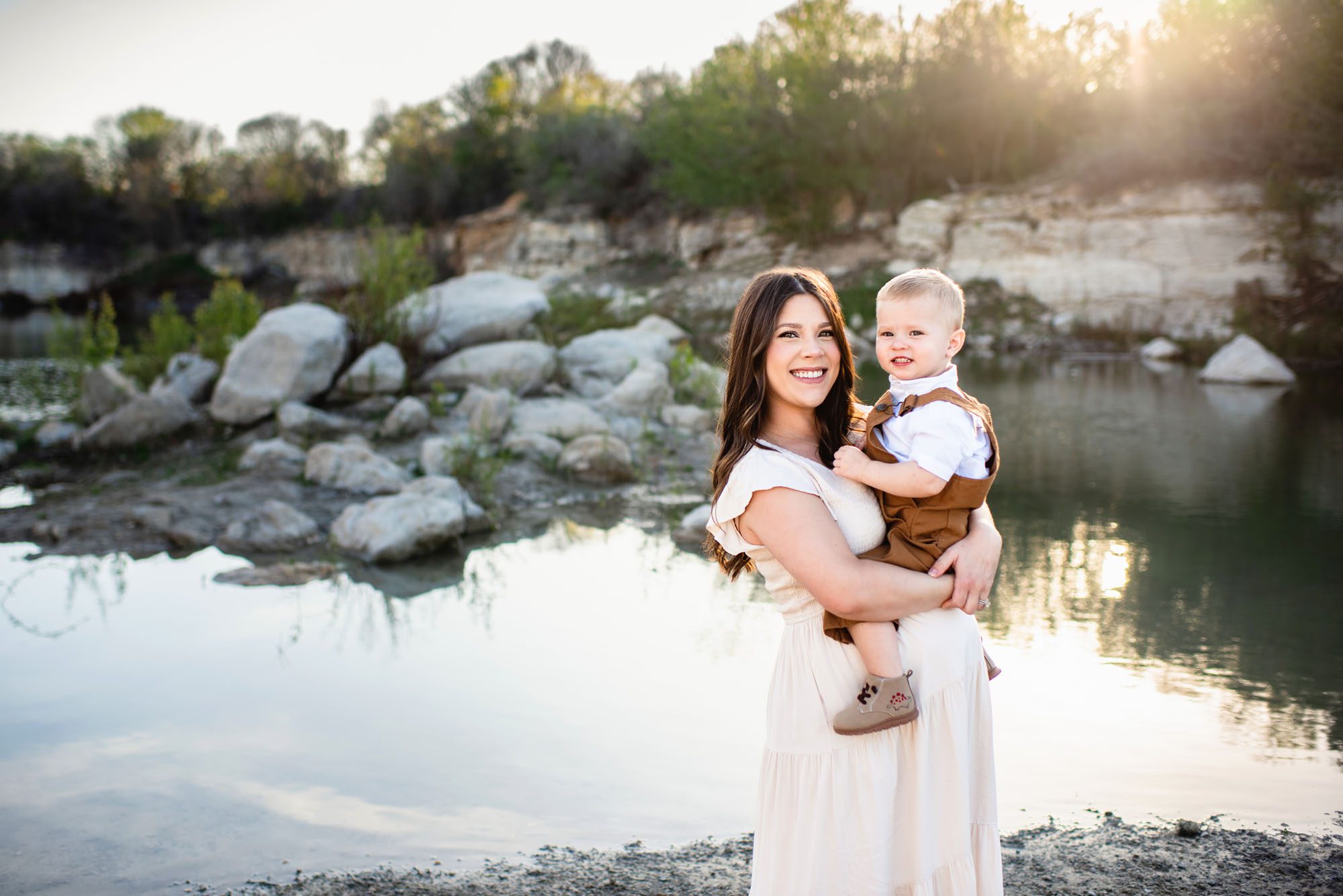 Pregnant mom holding toddler by a lake at sunset, San Antonio maternity photographer