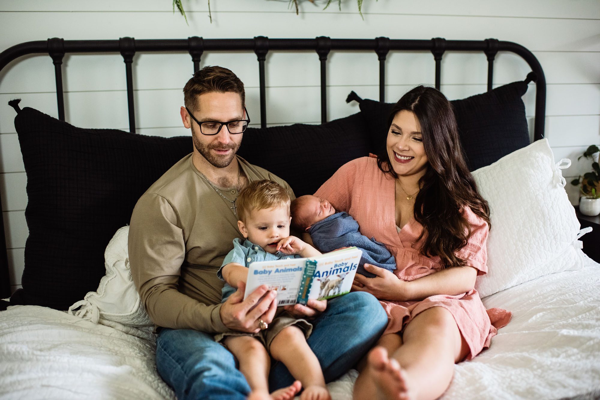Family reading together with newborn baby on bed, San Antonio newborn photographer