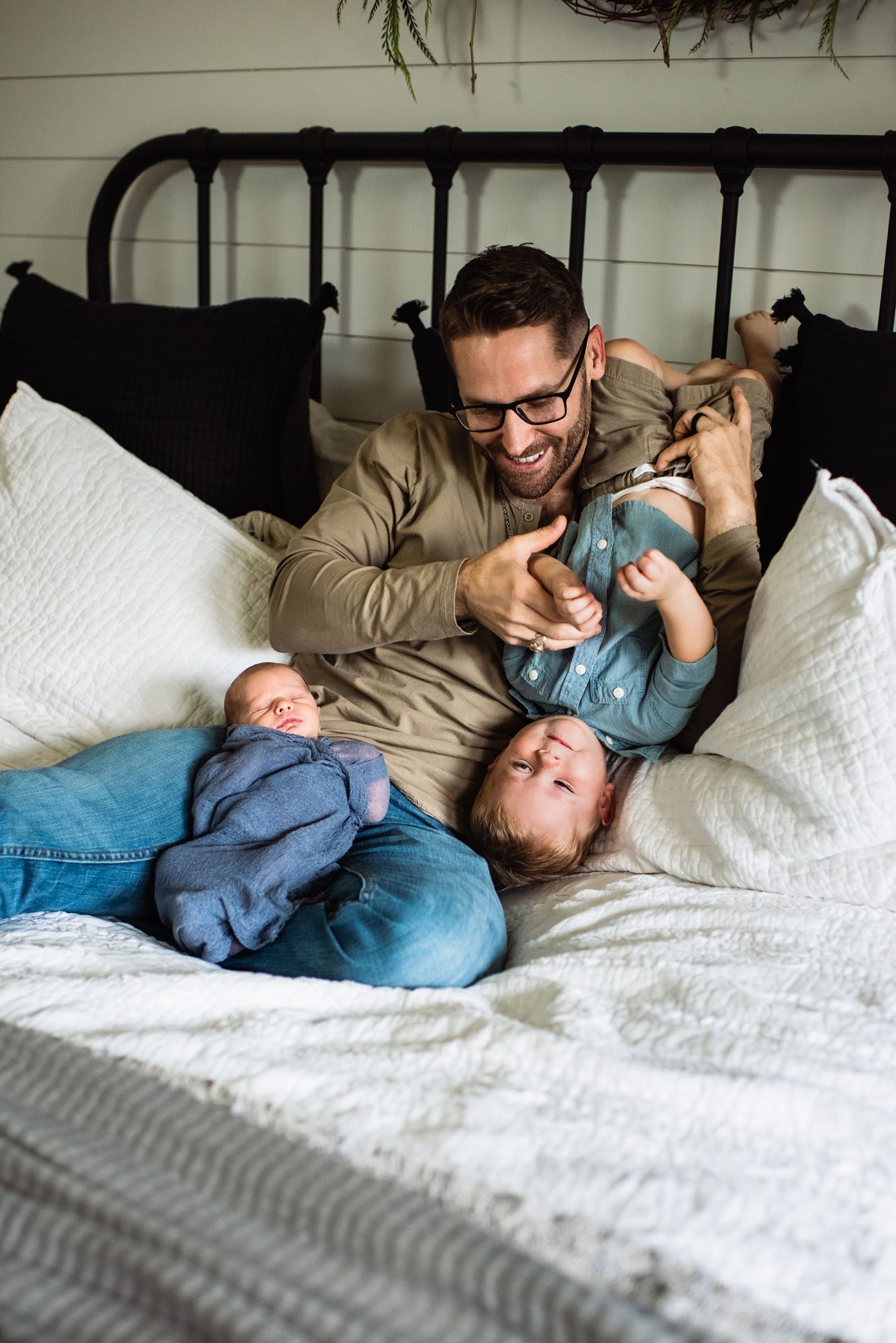 Dad playing with newborn baby boy and toddler on bed, San Antonio newborn photographer