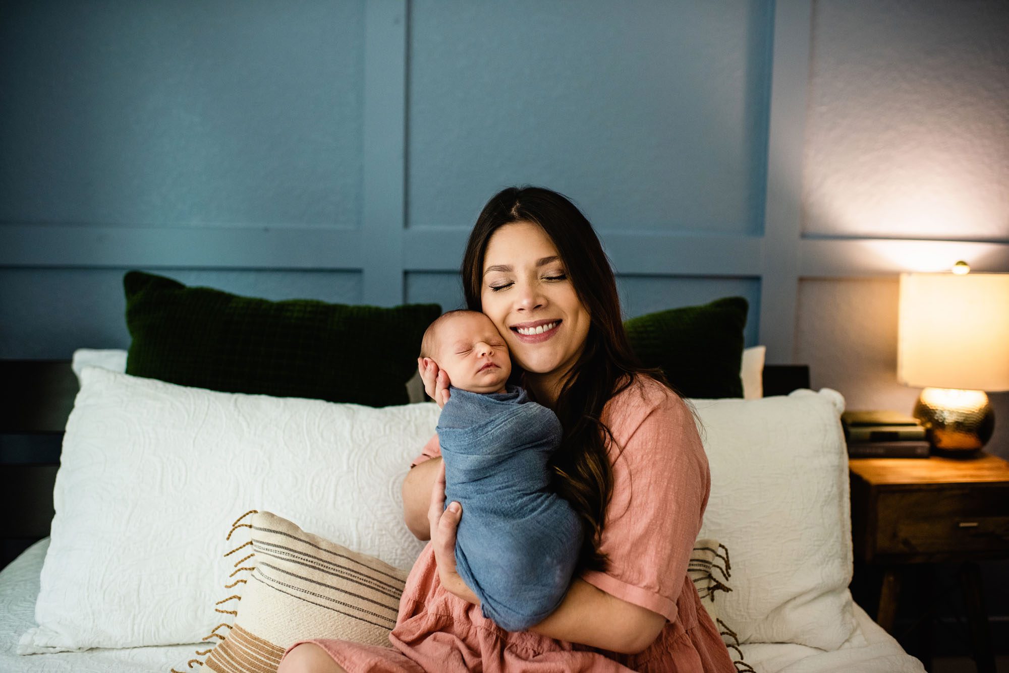 Mom smiling with newborn baby on bed, newborn photographer in San Antonio