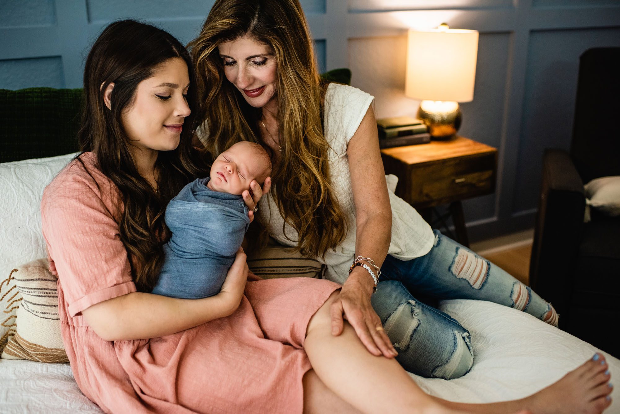 Mother and grandmother smiling at newborn baby on bed, newborn photographer in San Antonio
