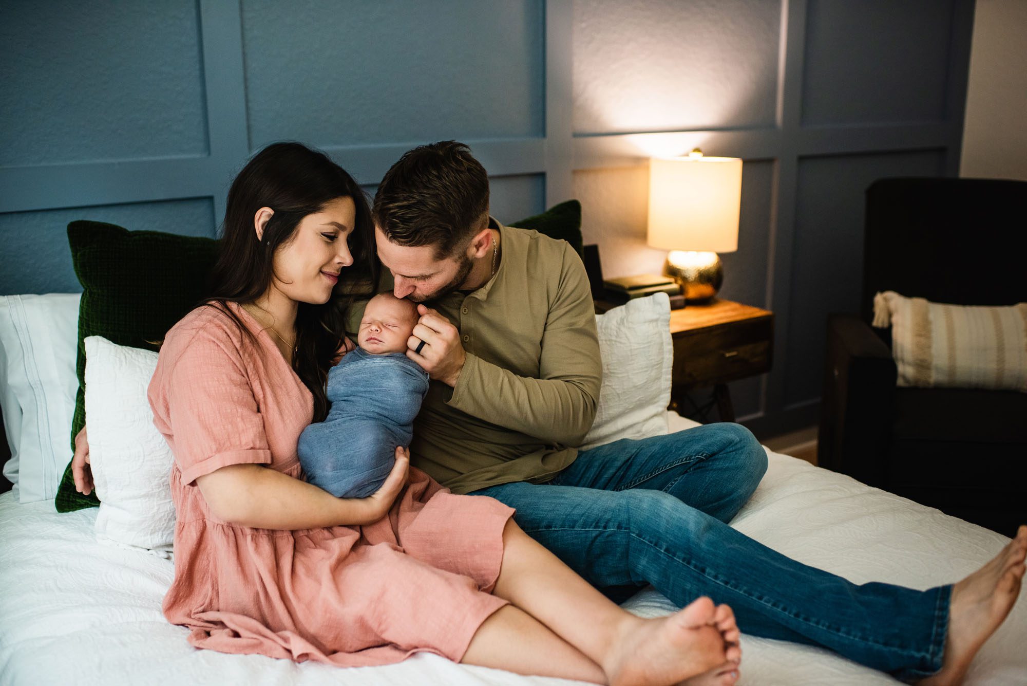 Couple smiling at newborn baby on bed, newborn photographer near me