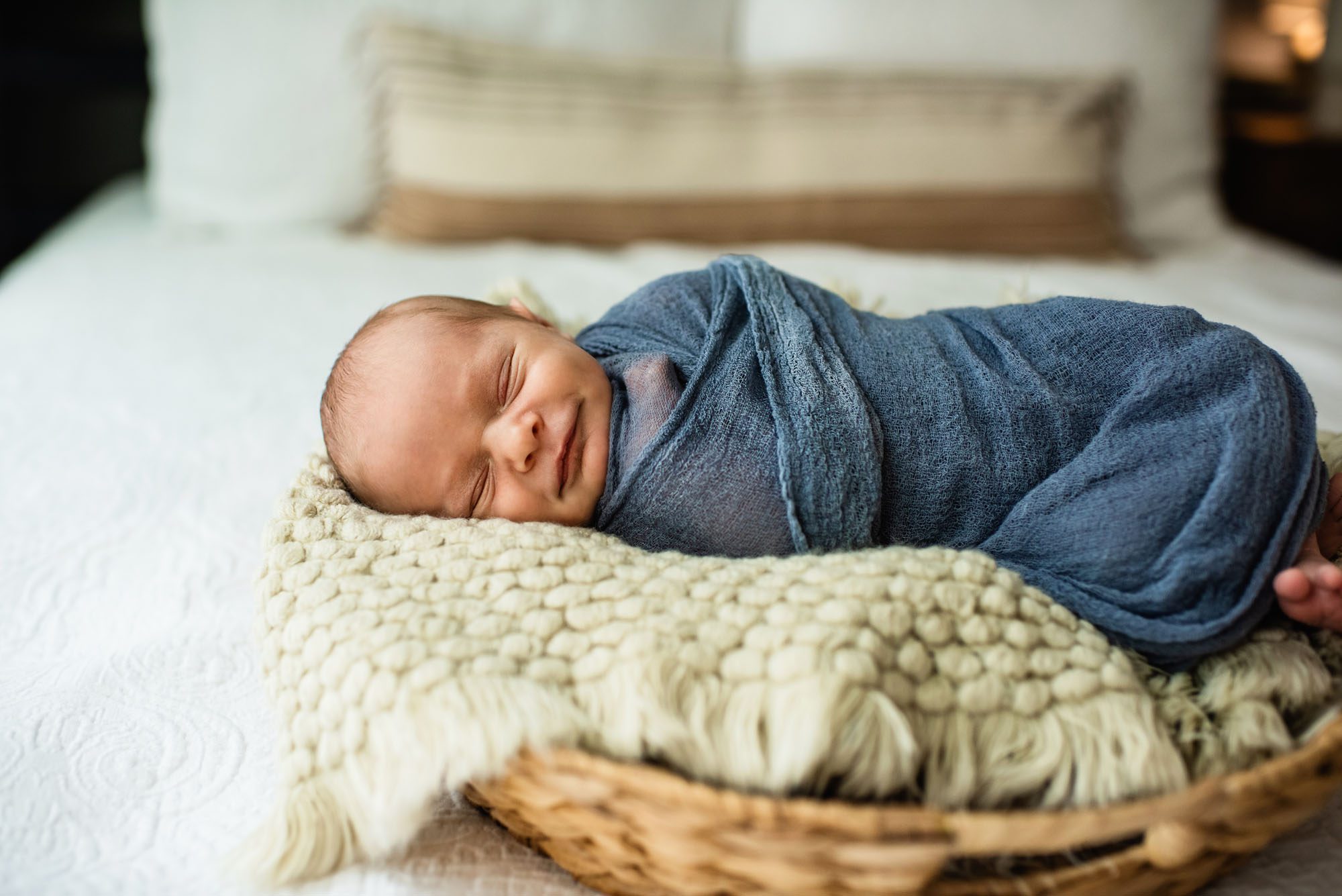 Baby boy smiling in his sleep swaddled in basket, San Antonio newborn photographer
