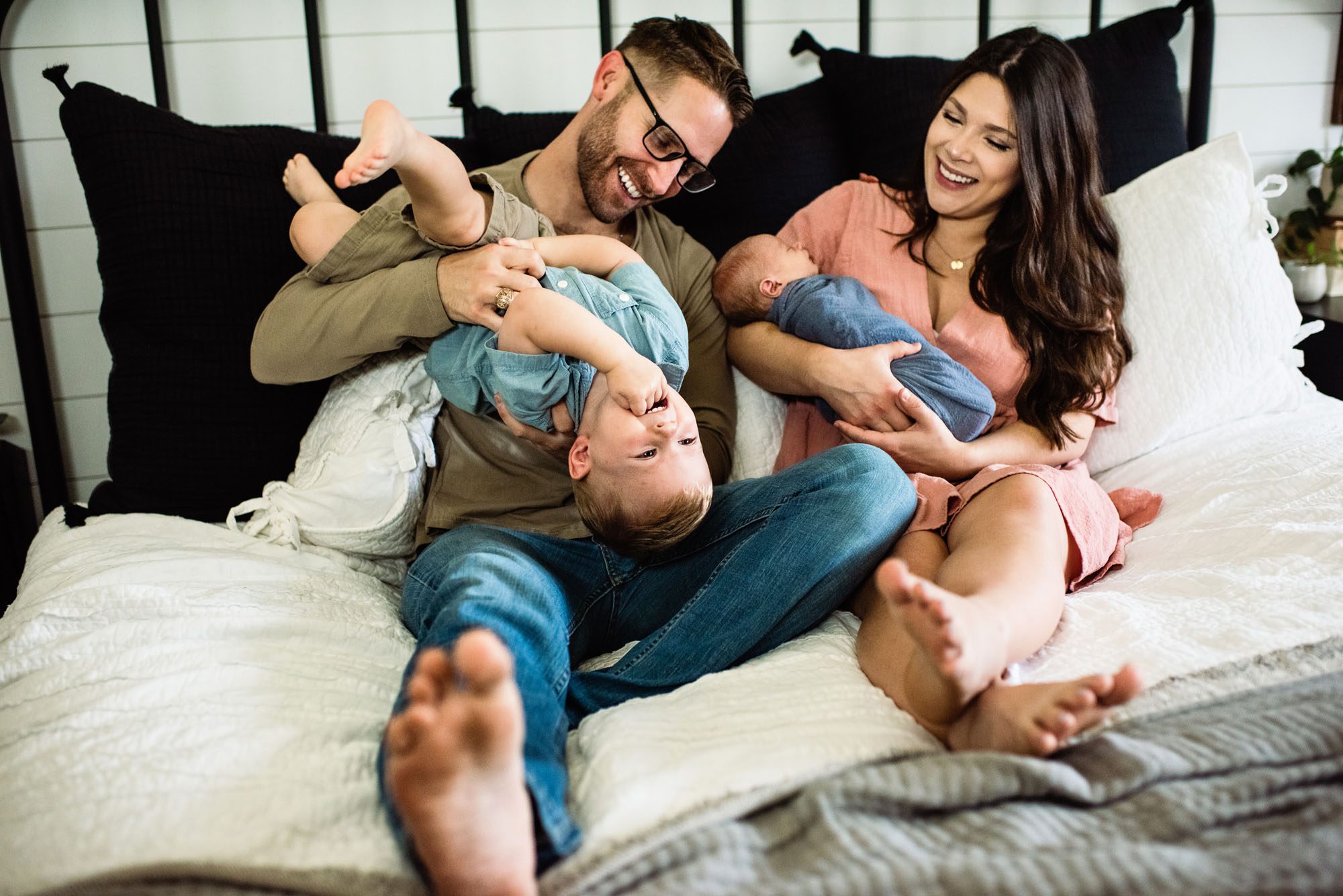 Family sitting together with newborn baby boy on bed, San Antonio newborn photographer