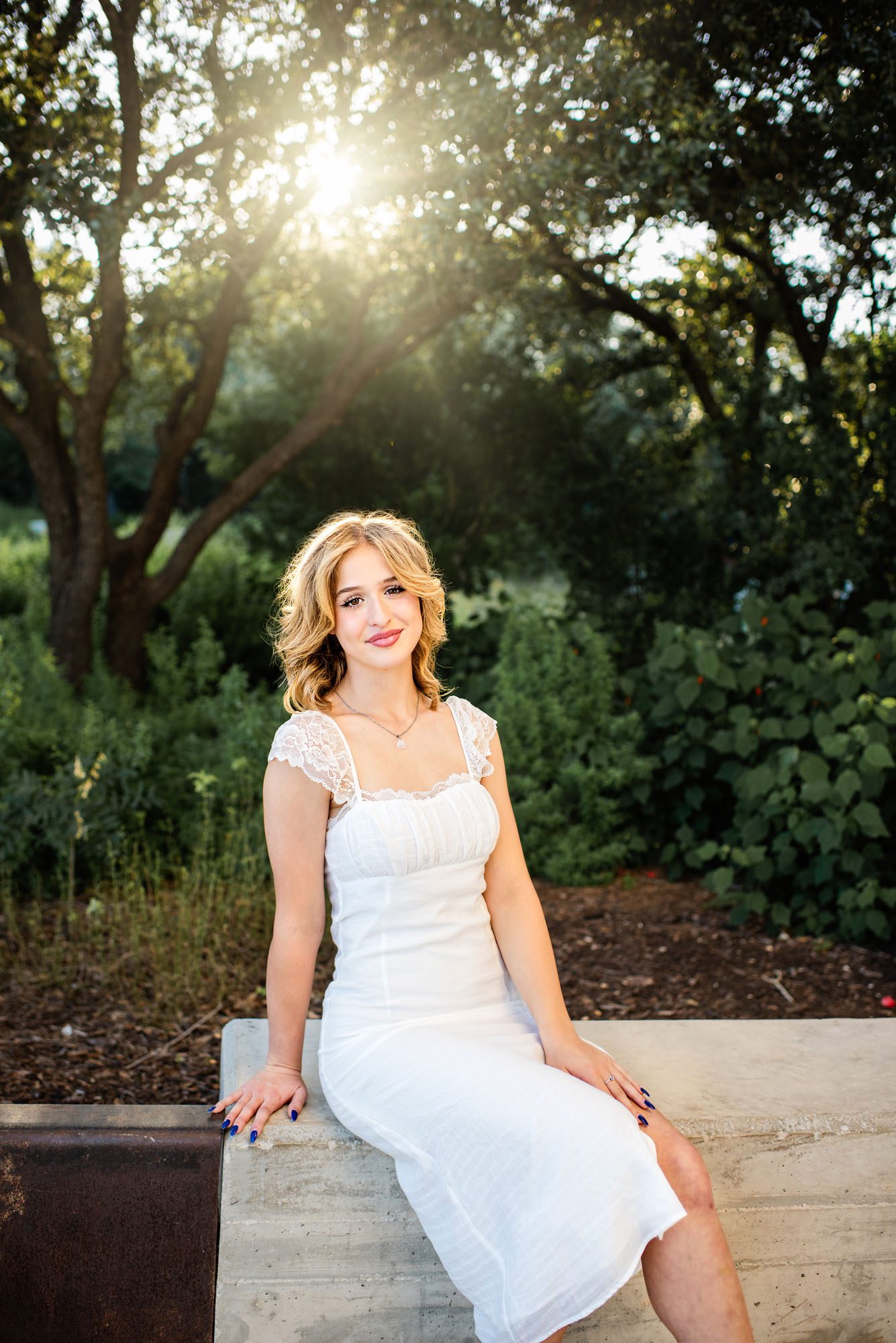 Senior girl in white dress sitting in front of trees, San Antonio senior photographer