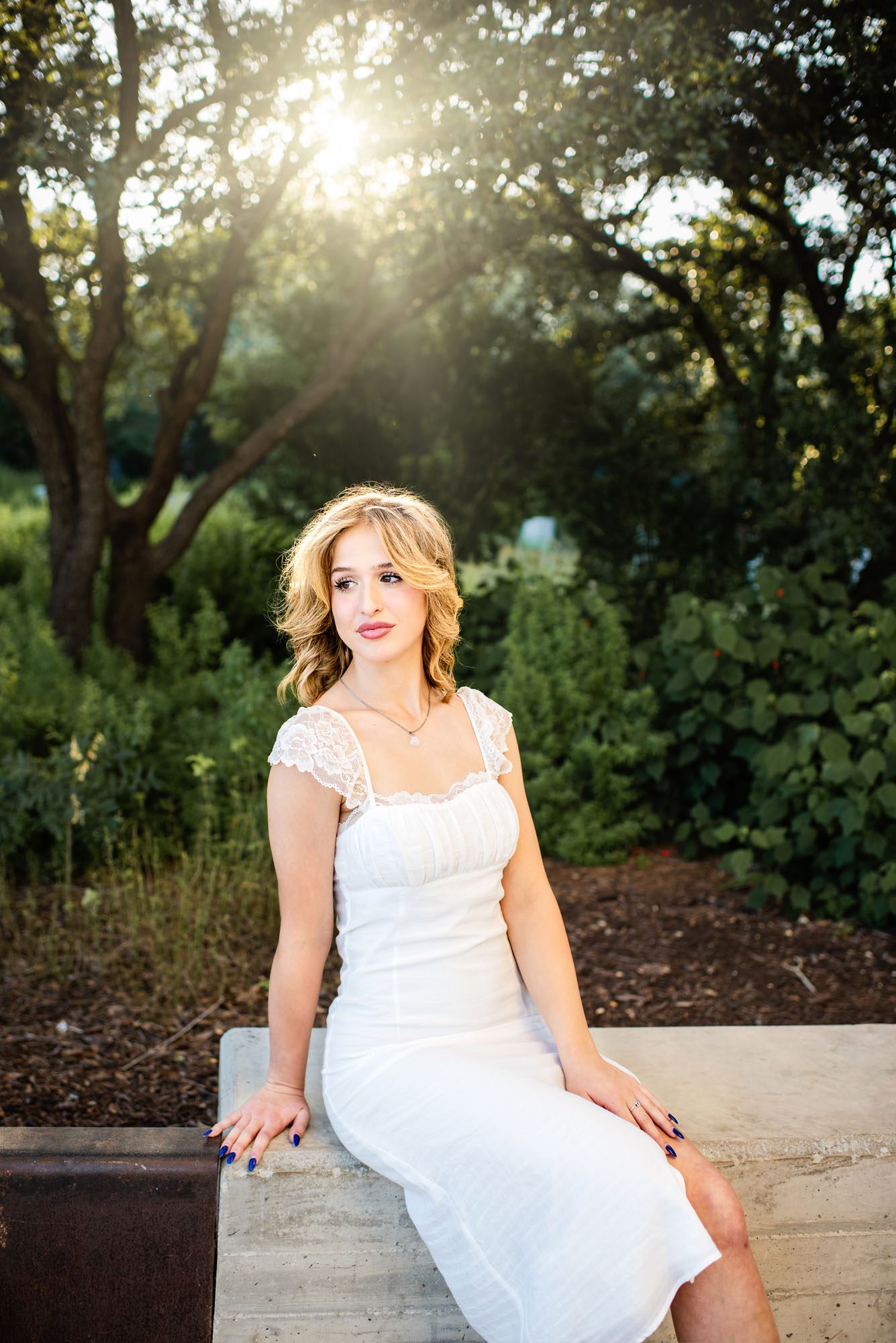Senior girl in white dress sitting in front of trees, San Antonio senior photographer