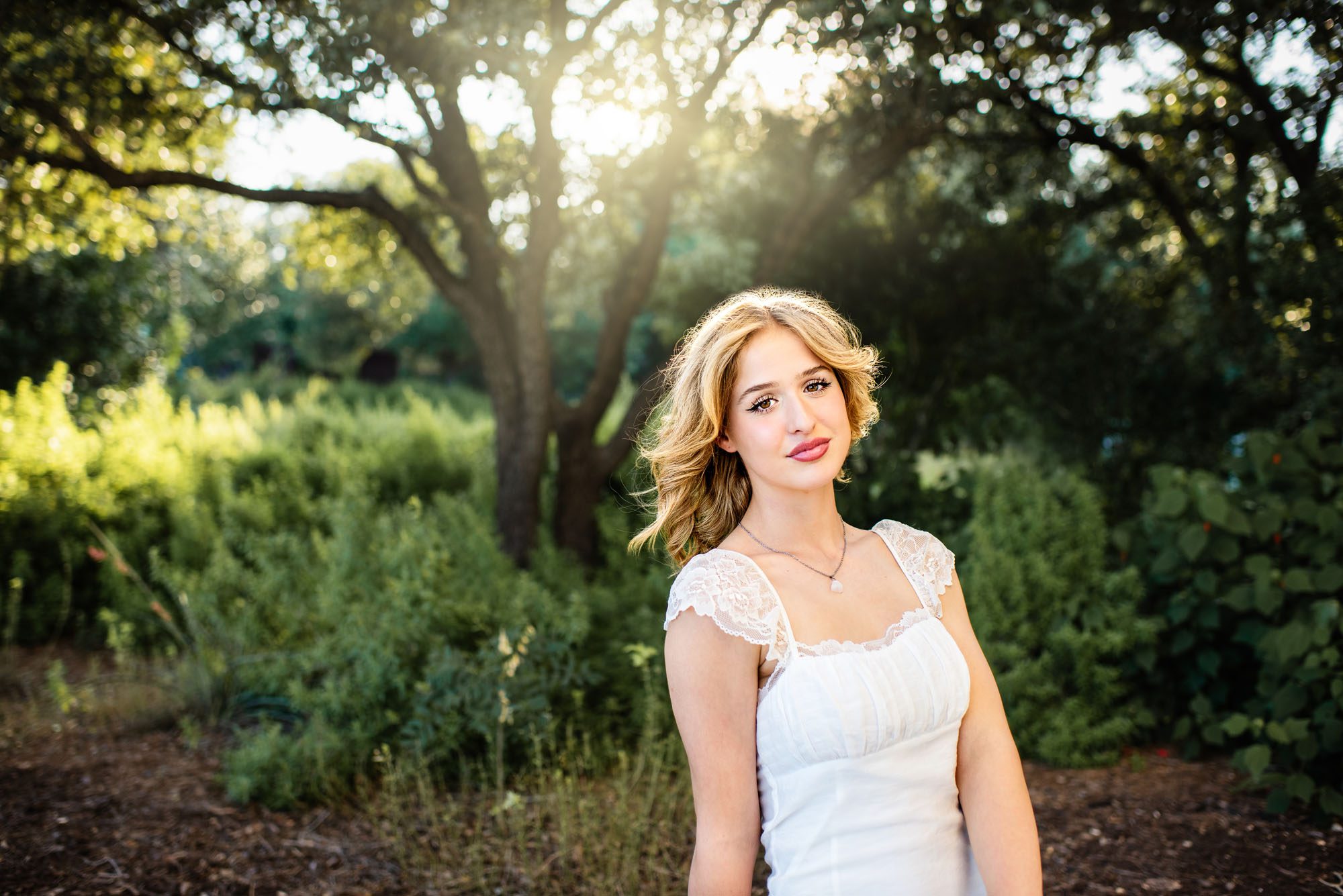 Senior girl in white dress in front of trees, San Antonio senior photographer