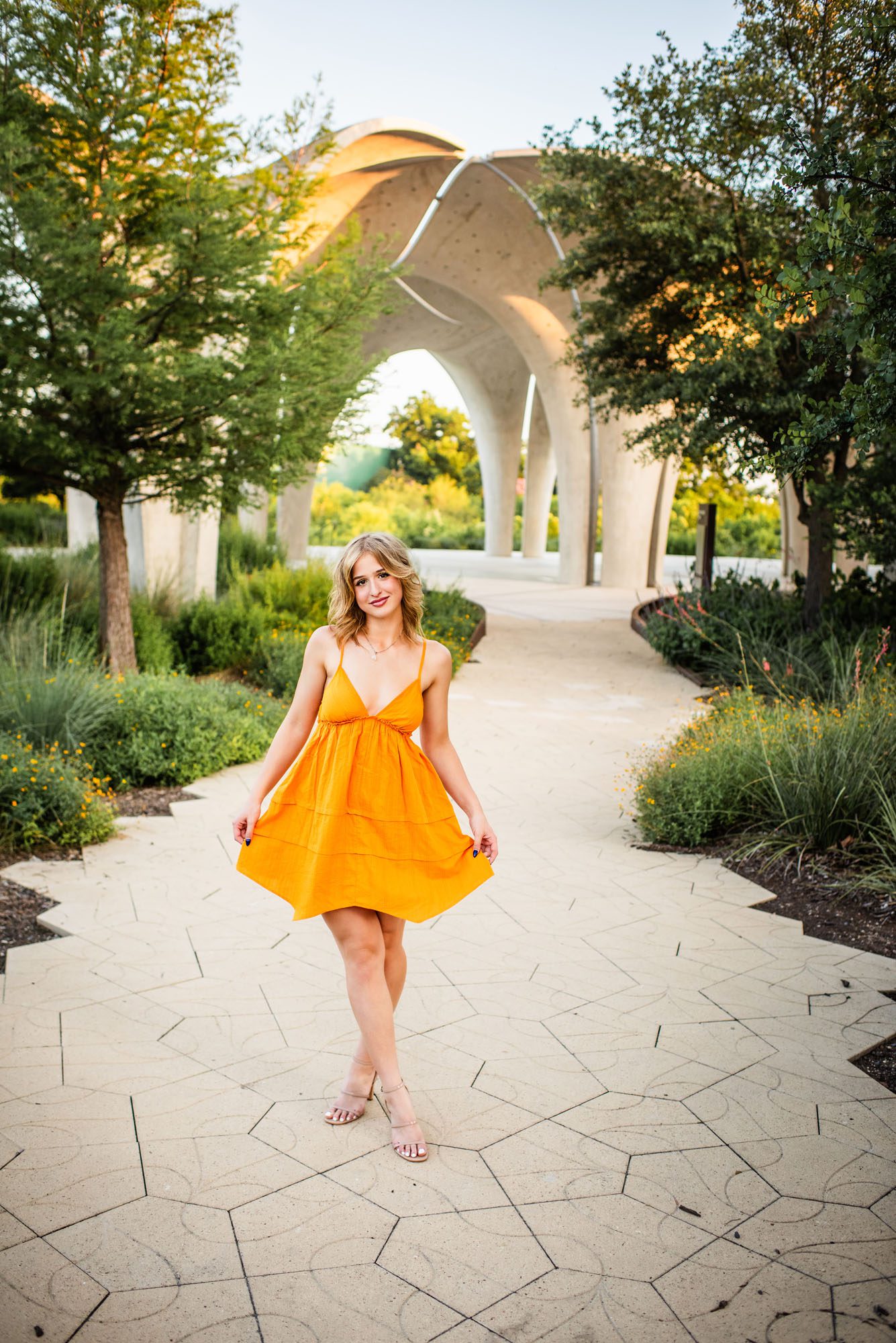 Senior in orange dress standing on path, San Antonio senior photography