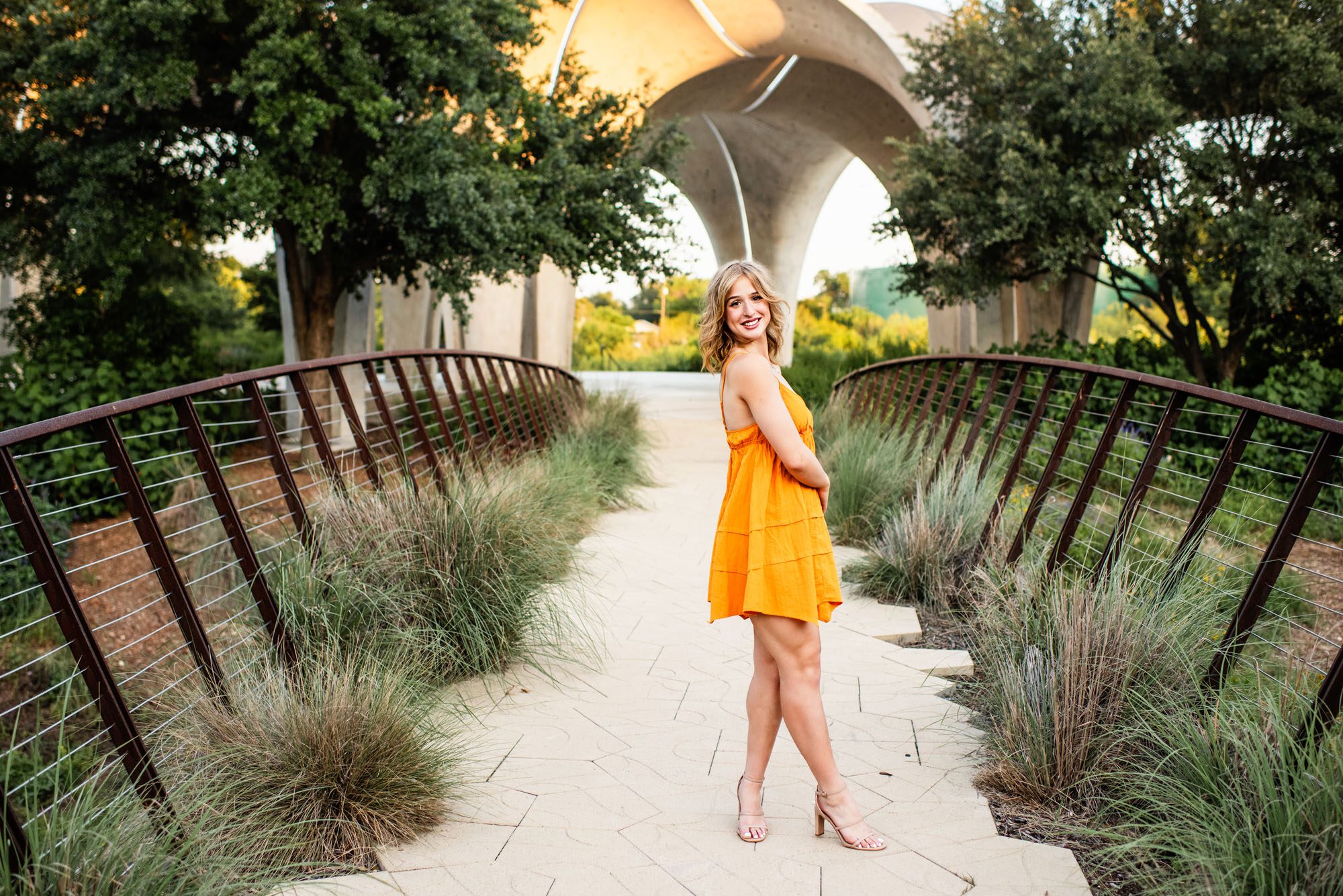 Girl in orange dress standing on bridge, best San Antonio senior photographer