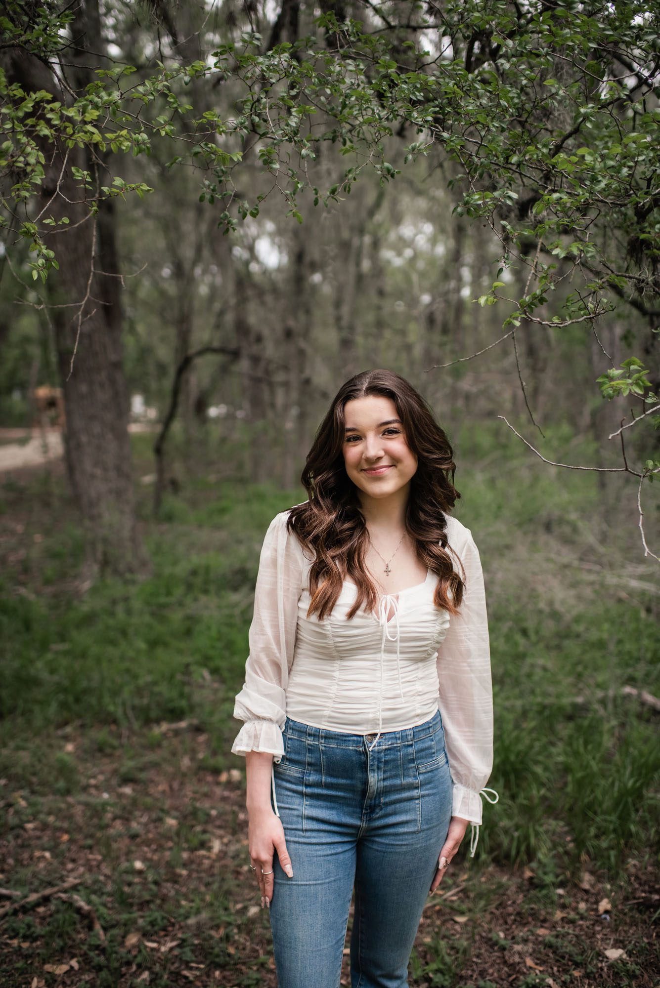 Girl in white shirt and jeans standing in forest, San Antonio senior photographer