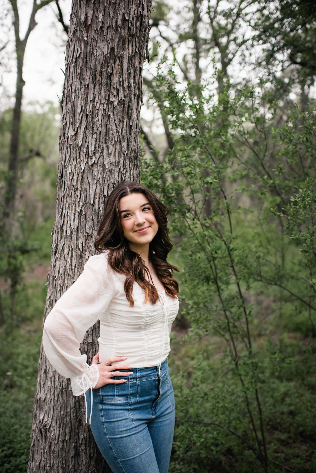 Girl in white shirt and jeans standing by tree, San Antonio senior photographer