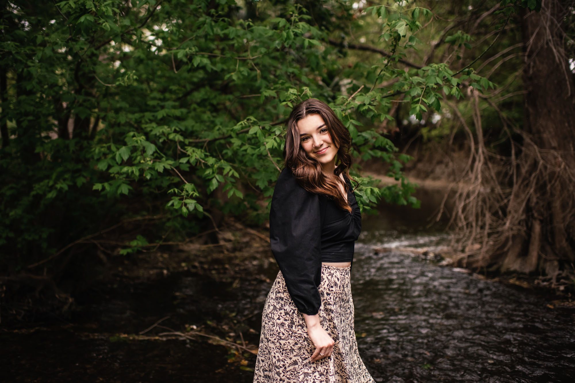 Girl standing in creek looking over her shoulder and smiling, San Antonio senior photographer
