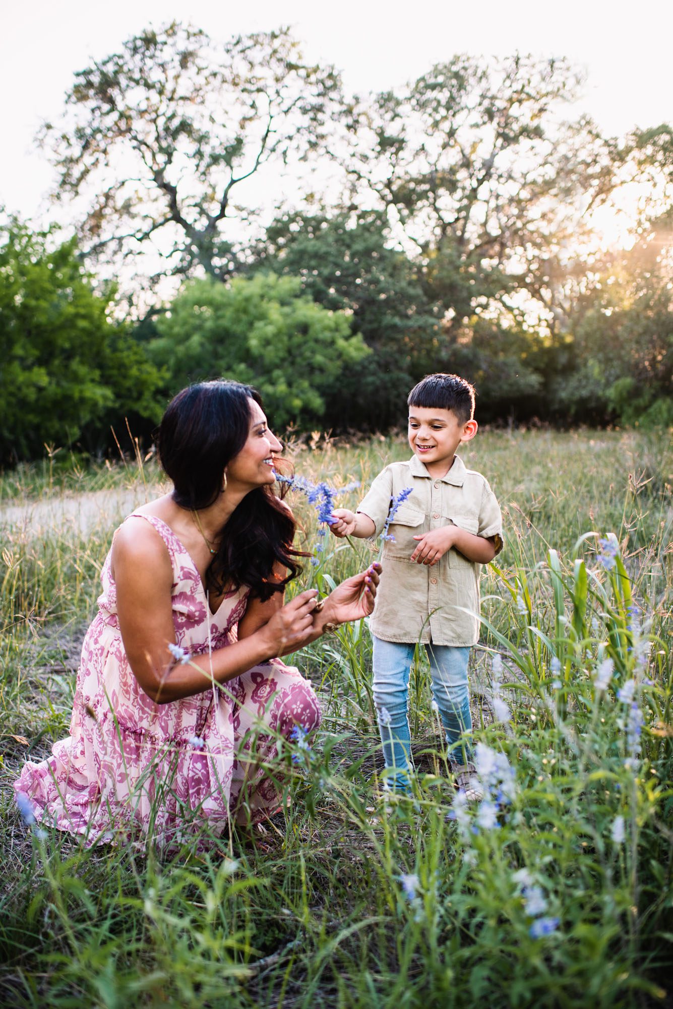 Mother and son smelling wildflowers in a field, San Antonio family photographer