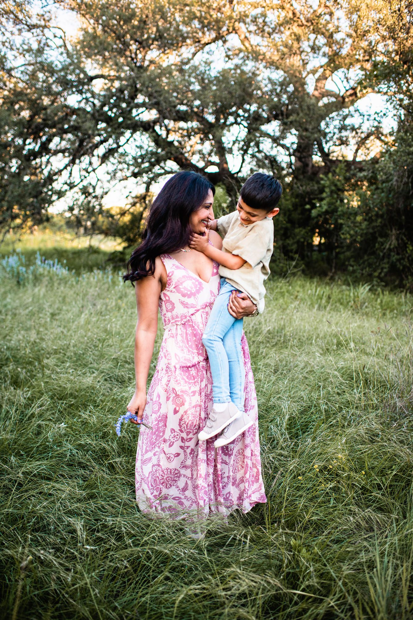 Mother and son hugging in grassy field with wildfowers, San Antonio family photographer