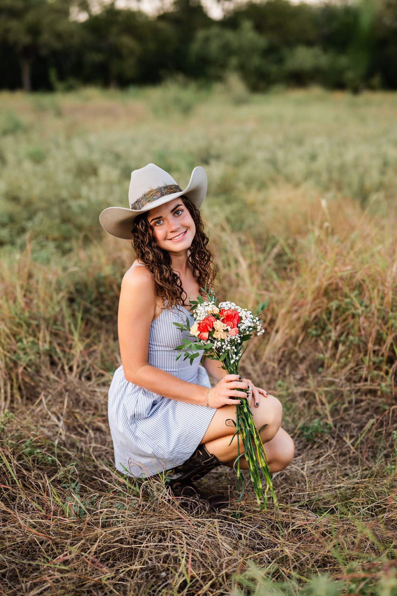 High school girl squatting in field, San Antonio senior photographer