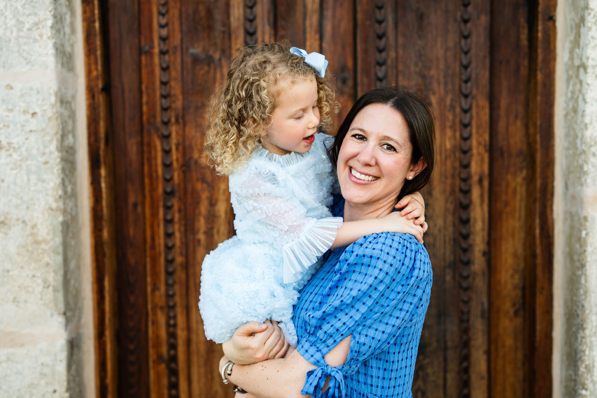 Mother holding daughter by wooden fdoor, San Antonio family maternity photographer
