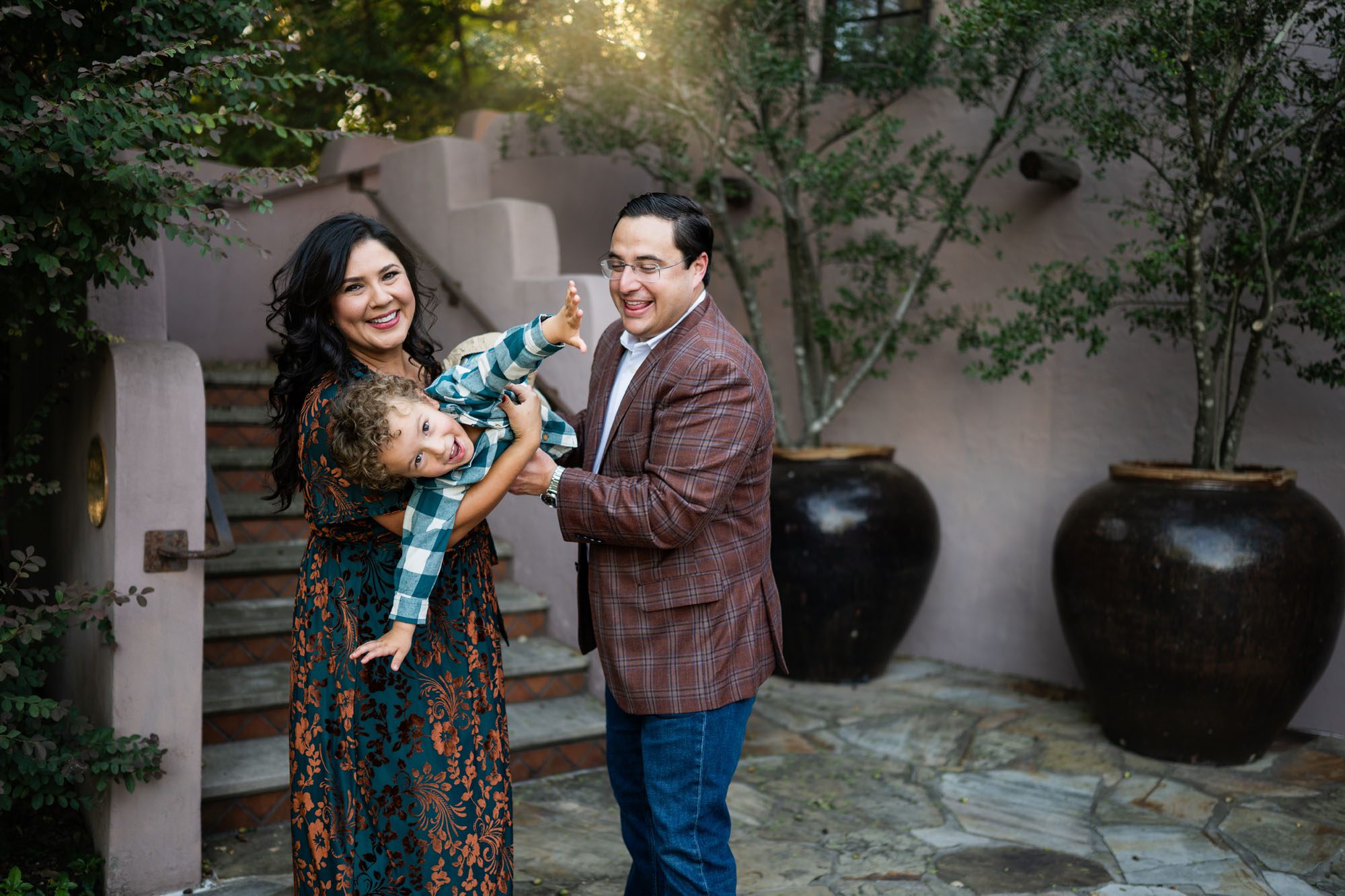 Little boy holding his arms out like an airplane while parents hold him, San Antonio family photographer