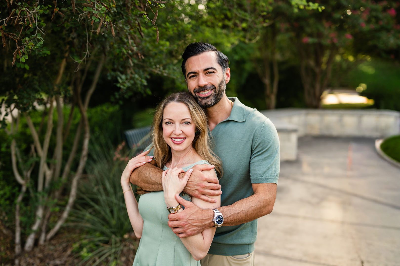 Couple hugging in front of green trees, San Antonio family photographer